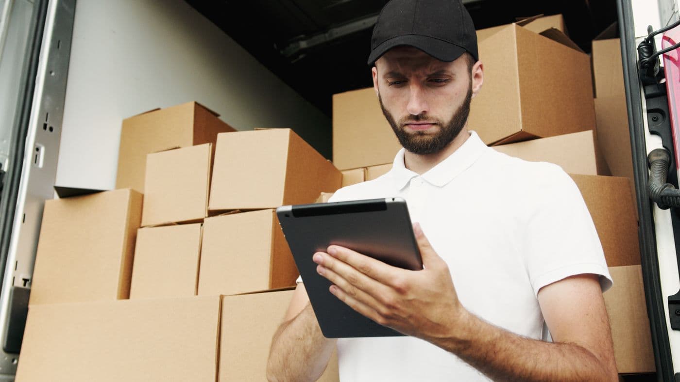 Responsable revisando en tablet la documentación del envío junto al vehículo de carga